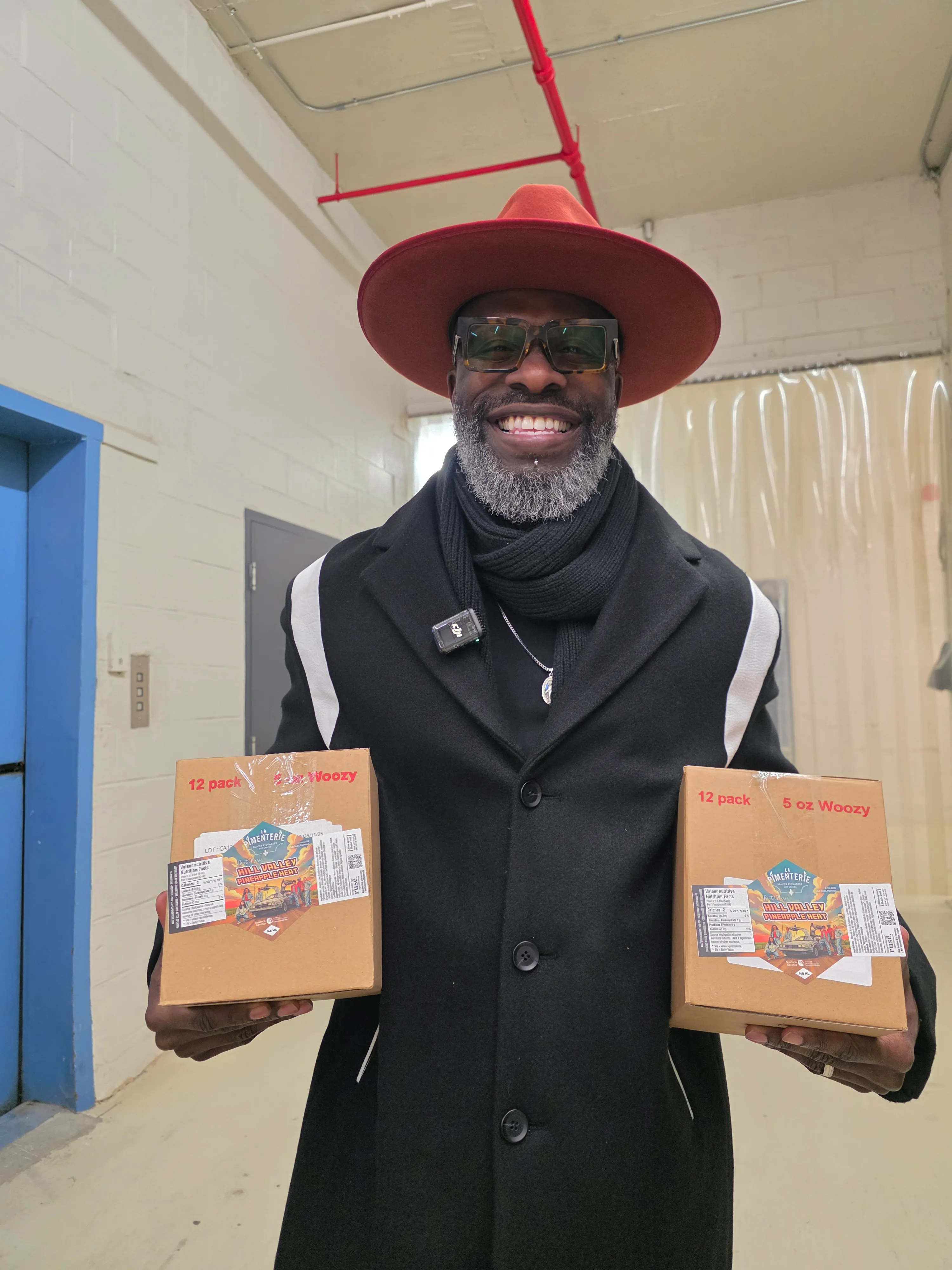 Two men dressed in red jackets shake hands in front of a DeLorean car with gull-wing doors open on a cloudy day.