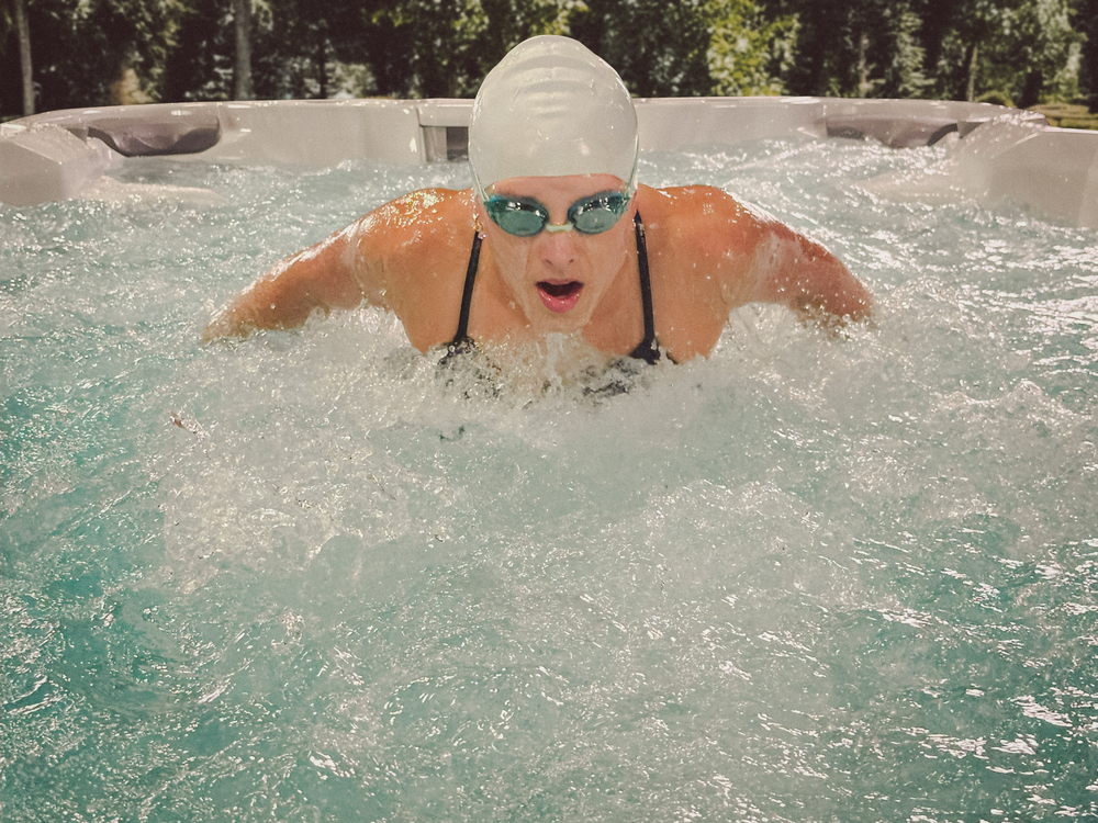 Woman exercising in a Sundance swim spa in her backyard