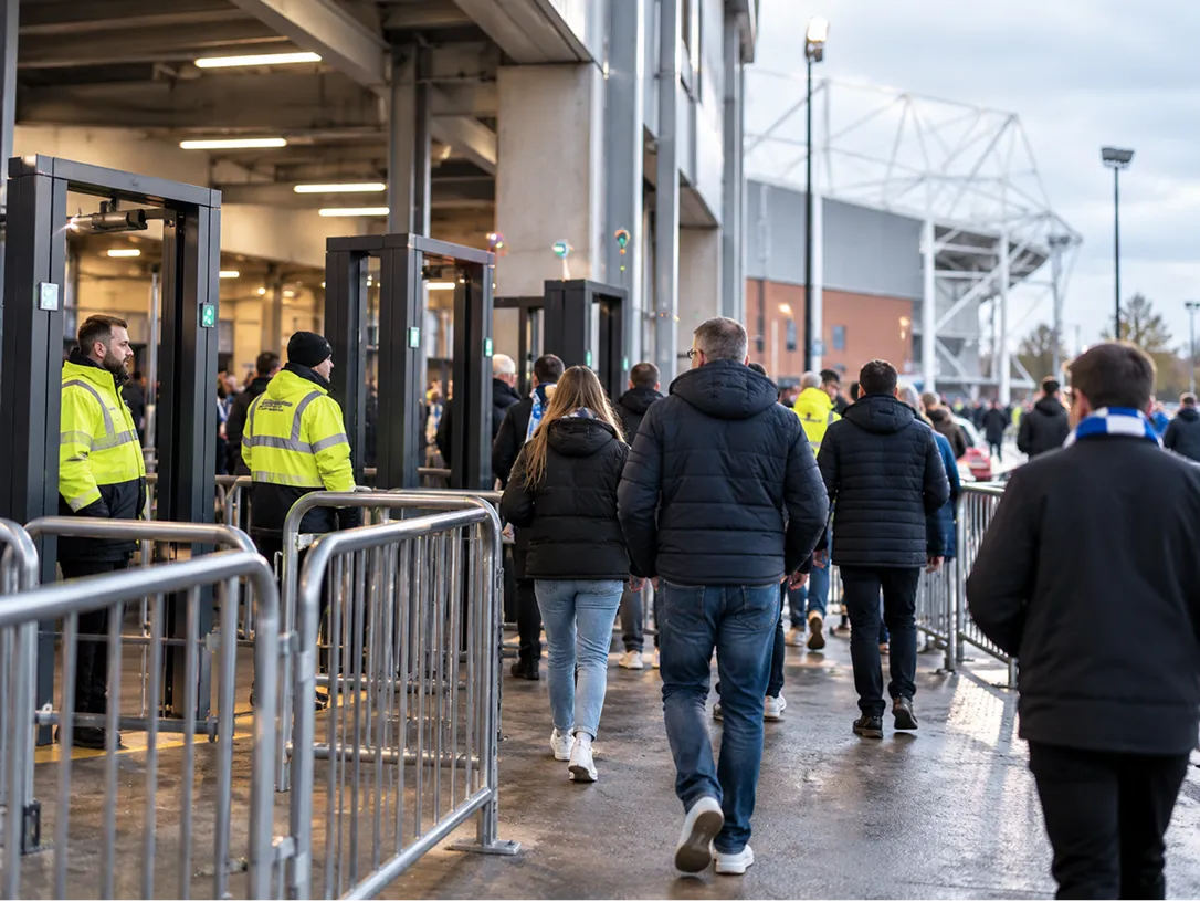 Football fans entering a stadium through security gates