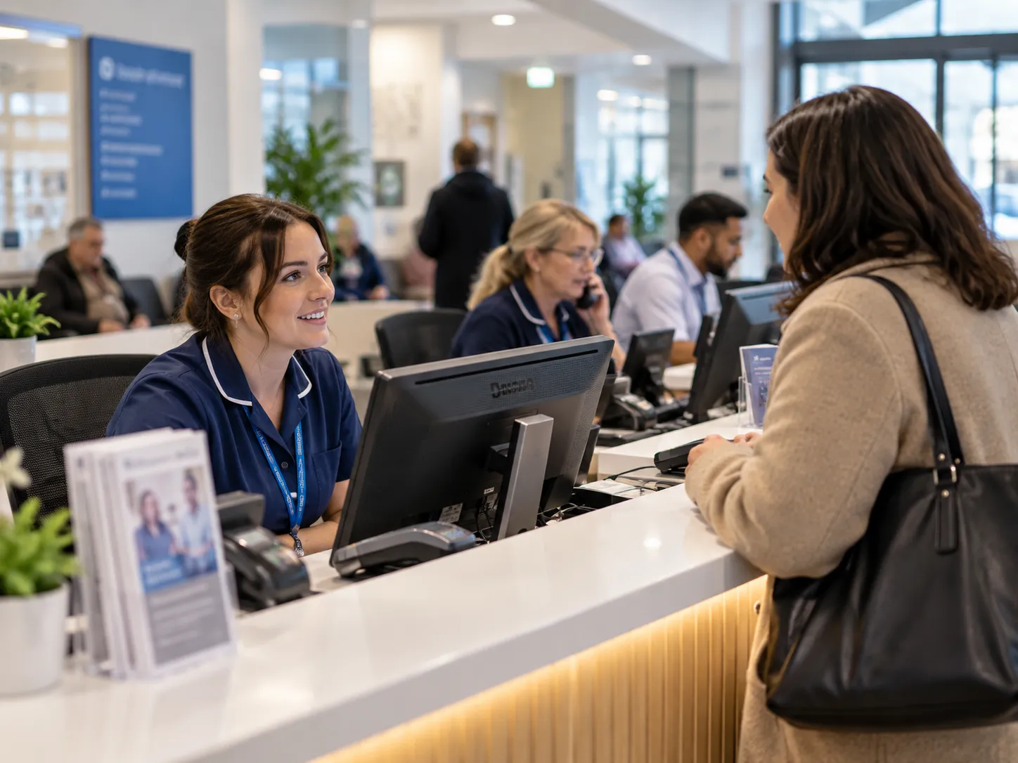 Staff at a healthcare reception desk helping a visitor