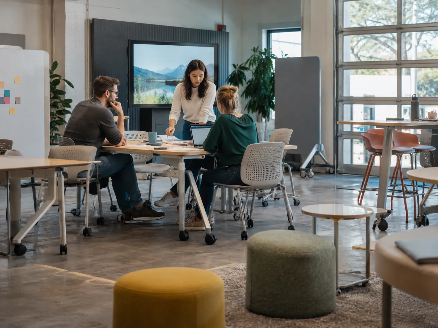 Colleagues working in a flexible meeting space with a wall-mounted display