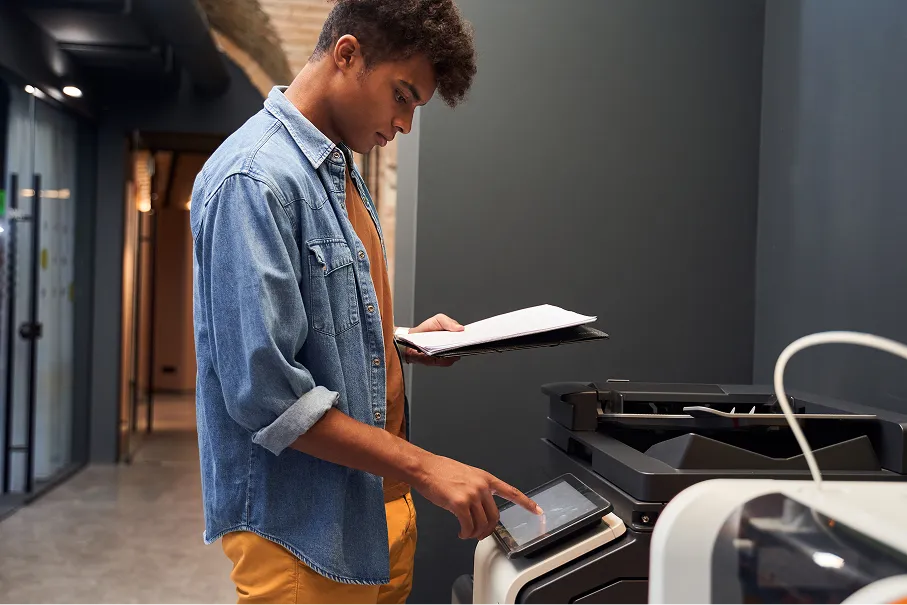 Man using the touchscreen on an office multifunction printer