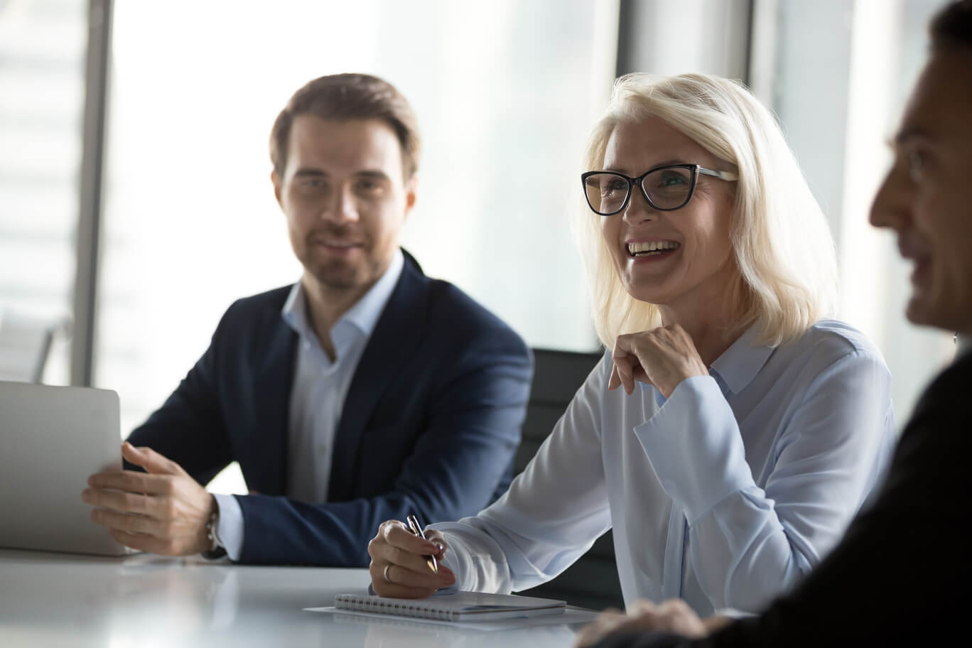 Successful positive businessmen and businesswoman sitting negotiating in boardroom.