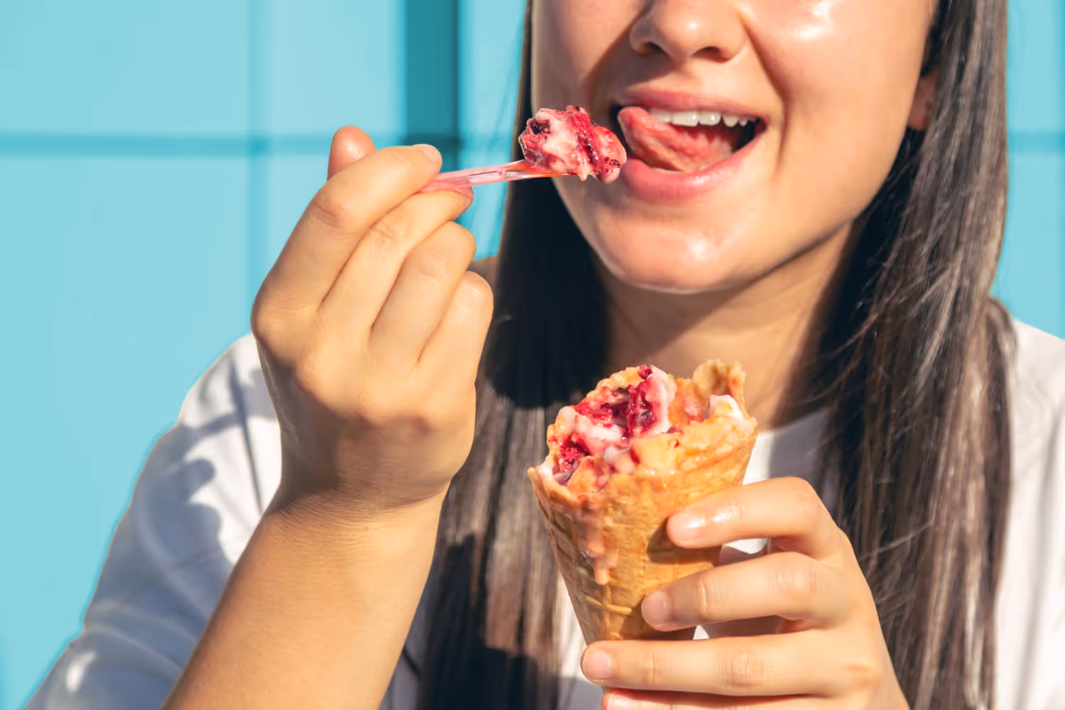 A woman eating a dessert with a spoon.