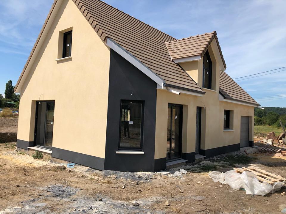 Maison beige de construction récente avec des accents sombres autour des fenêtres et des portes.