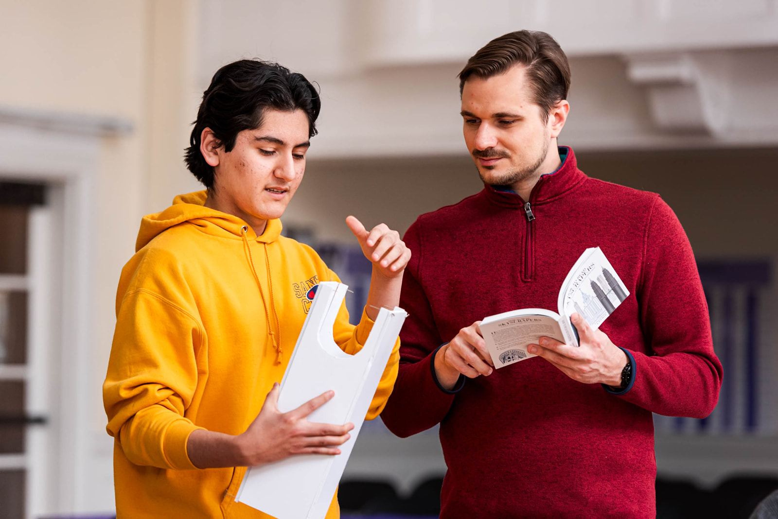 Two men are intently observing an object or scene in front of them.