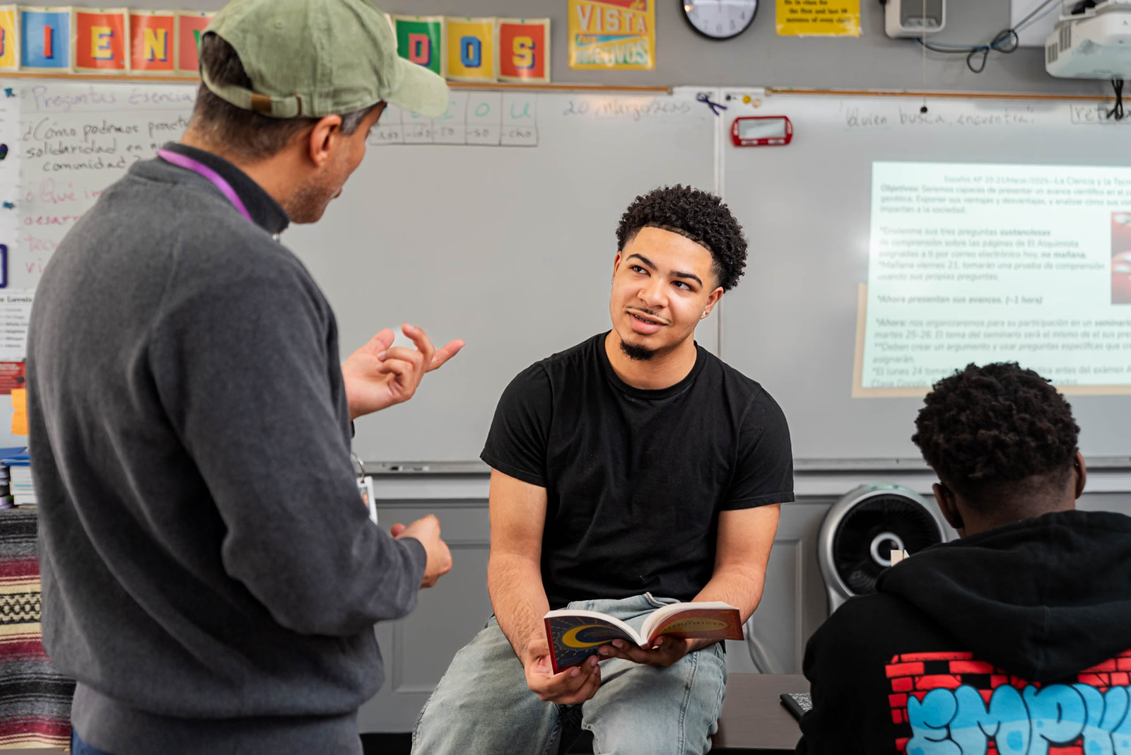 A man addresses a group of attentive students in a classroom setting.