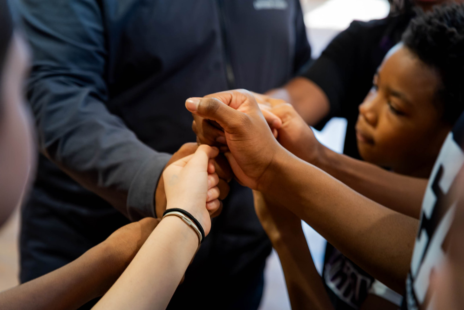 Group of diverse people joining hands together in a gesture of unity and teamwork.
