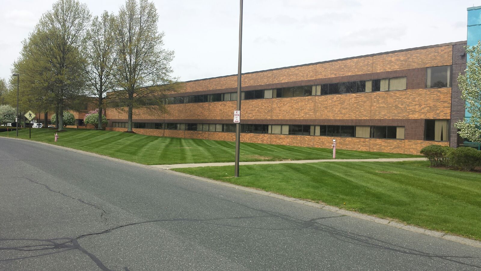 Two-story brick office building with large windows and a neatly mowed lawn beside a paved road.