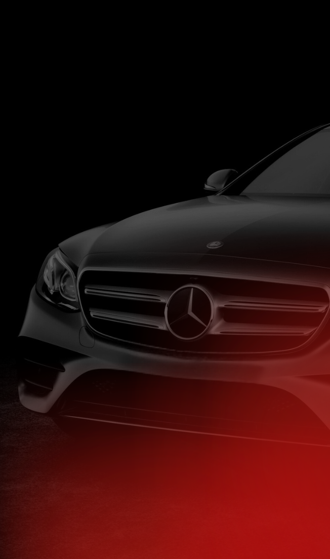 Front view of a black Mercedes-Benz car with a large emblem on the grill, set against a dark background with red lighting at the bottom.