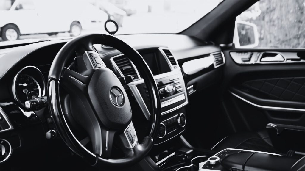 Person wearing gloves polishing the black car's exterior with a microfiber cloth.