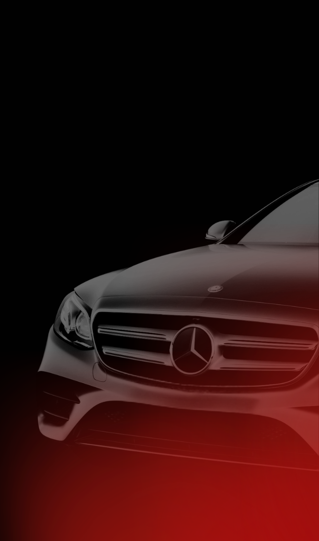 Close-up view of the front grille and emblem of a black Mercedes-Benz car with dark background.