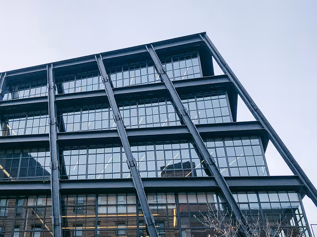 Modern multi-story building with large glass windows and diagonal external steel supports.