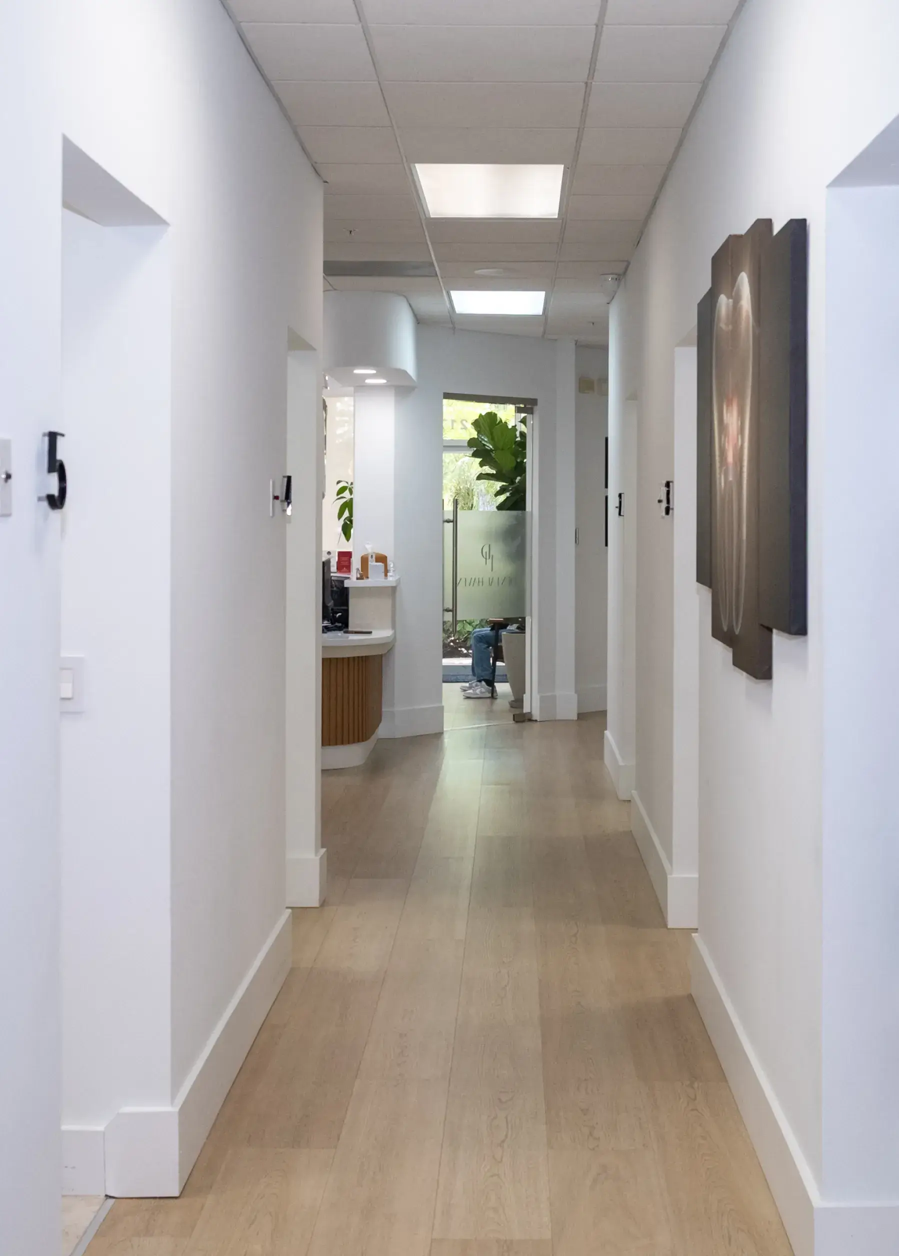 Hallway in an office with numbered doors and a reception area at the end.