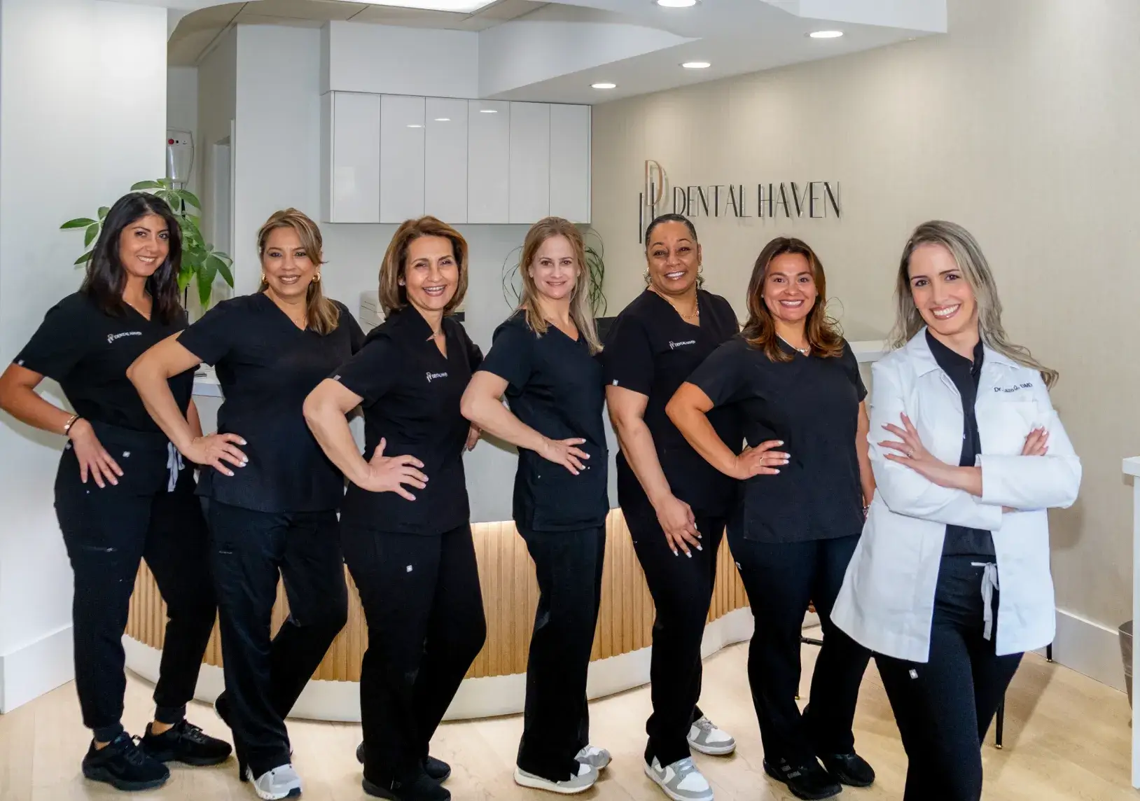 A group of seven dental professionals poses together in a dental office, smiling at the camera.