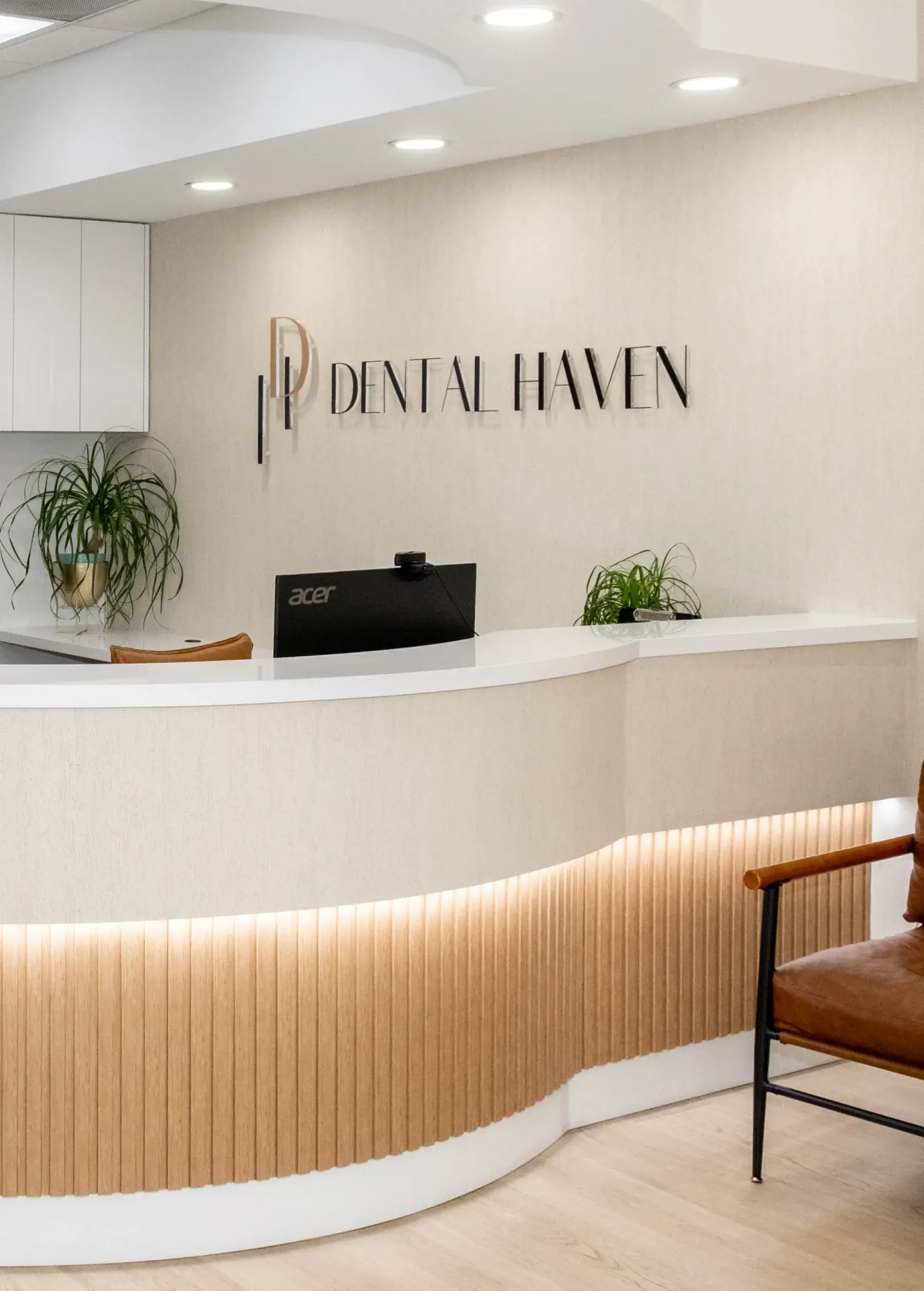 Reception desk at a dental office with a "Dental Haven" sign and plants on the counter.