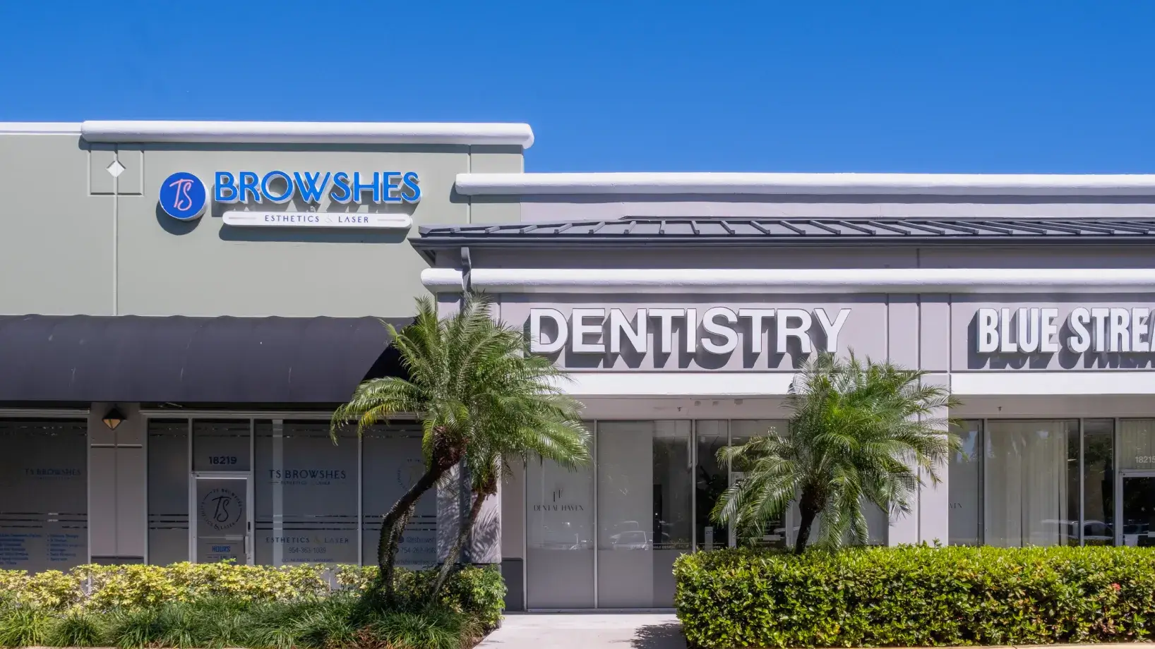Front view of a building with signs for a dentistry clinic and an aesthetics and laser clinic.