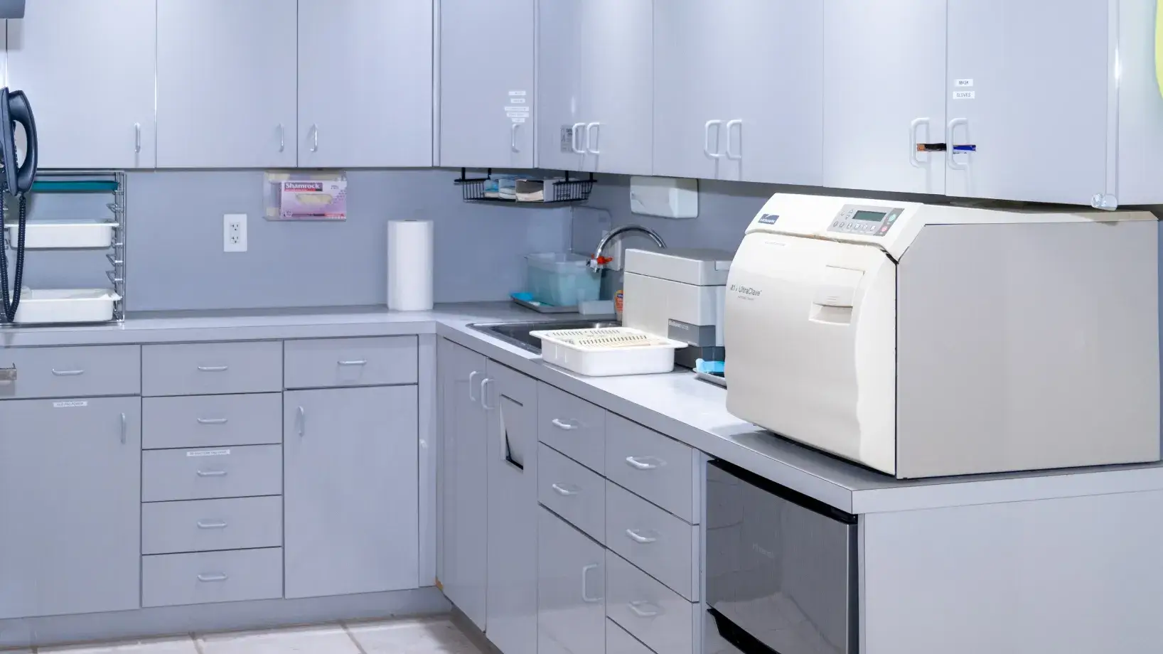 A clean, modern laboratory with gray cabinets and an autoclave machine on the countertop.