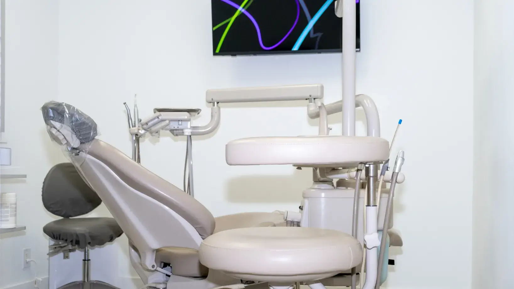 A clean, empty dentist's chair and equipment in a bright dental office.