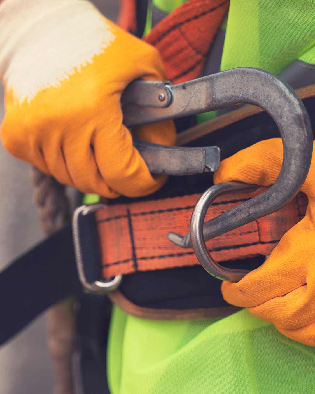 A close up photo of a roofing professional fastening a safety harness