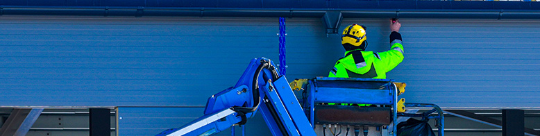 A roofing professional on a scissor lift repairing a roof