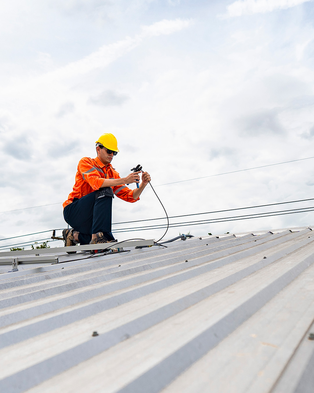 image of a professional roofer wearing safety equipment and splicing wire.