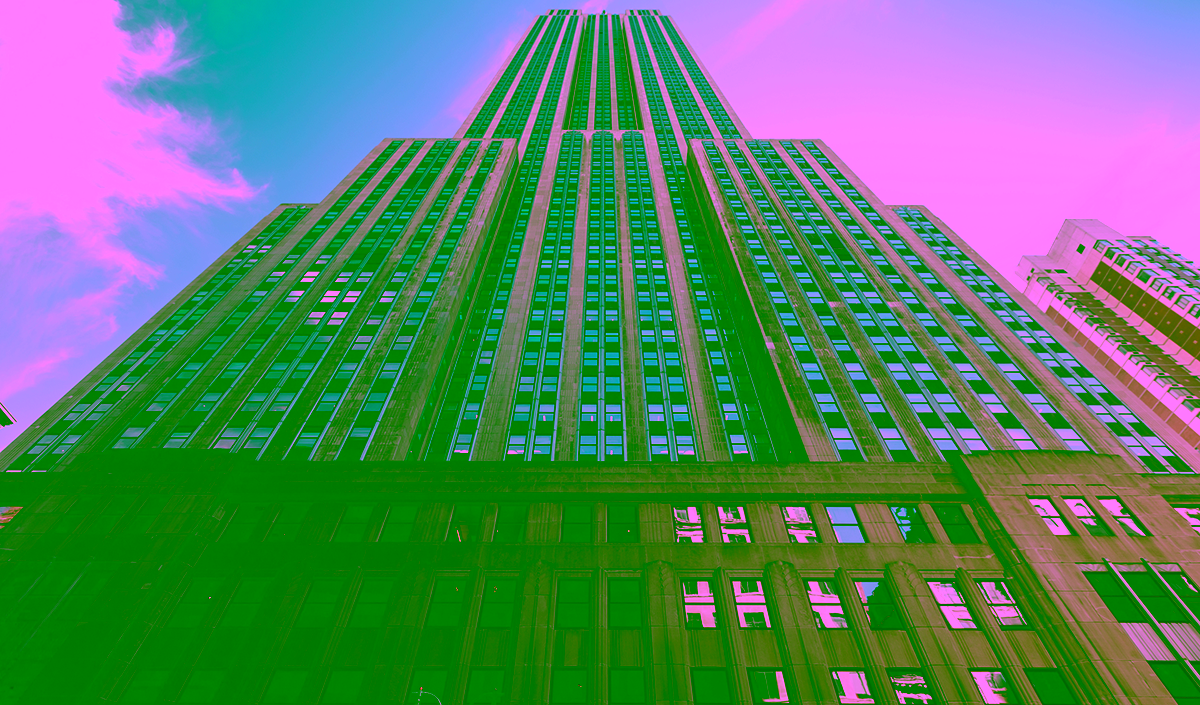 Low-angle view of a tall skyscraper with a stepped design and many windows under a partly cloudy sky.