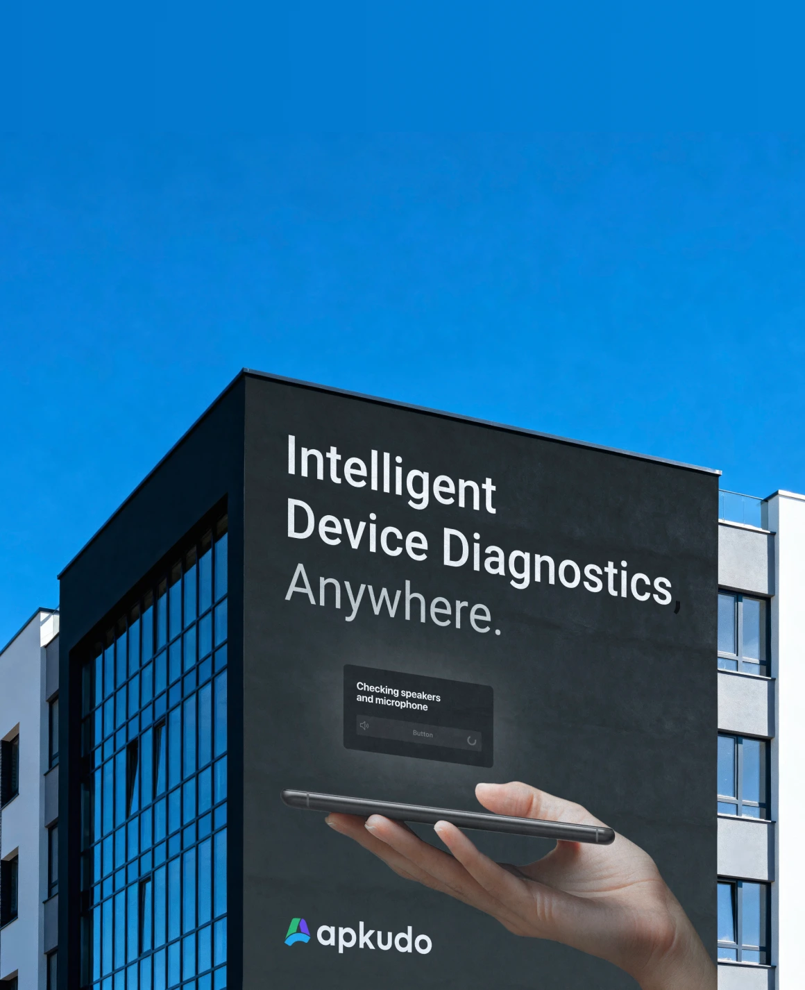 Building wall mural showing a hand holding a smartphone with the text 'Intelligent Device Diagnostics, Anywhere.' and the Apkudo logo.
