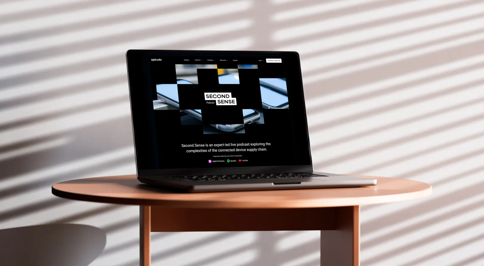 Laptop on a round wooden table displaying the Second Sense podcast homepage about connected device supply chain complexities.