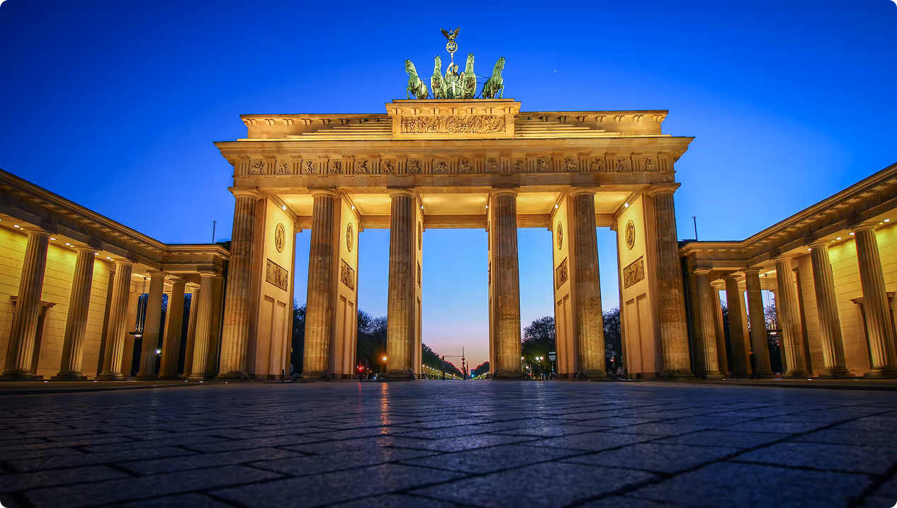 Das Brandenburger Tor in Berlin bei Dämmerung mit beleuchteten Säulen und blauem Himmel.