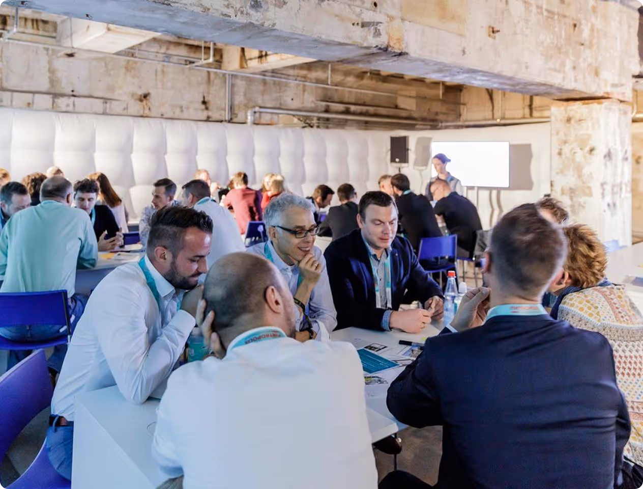 Mehrere Menschen sitzen an Tischen in einem Veranstaltungsraum und führen Diskussionen in einer Arbeitsgruppe.
