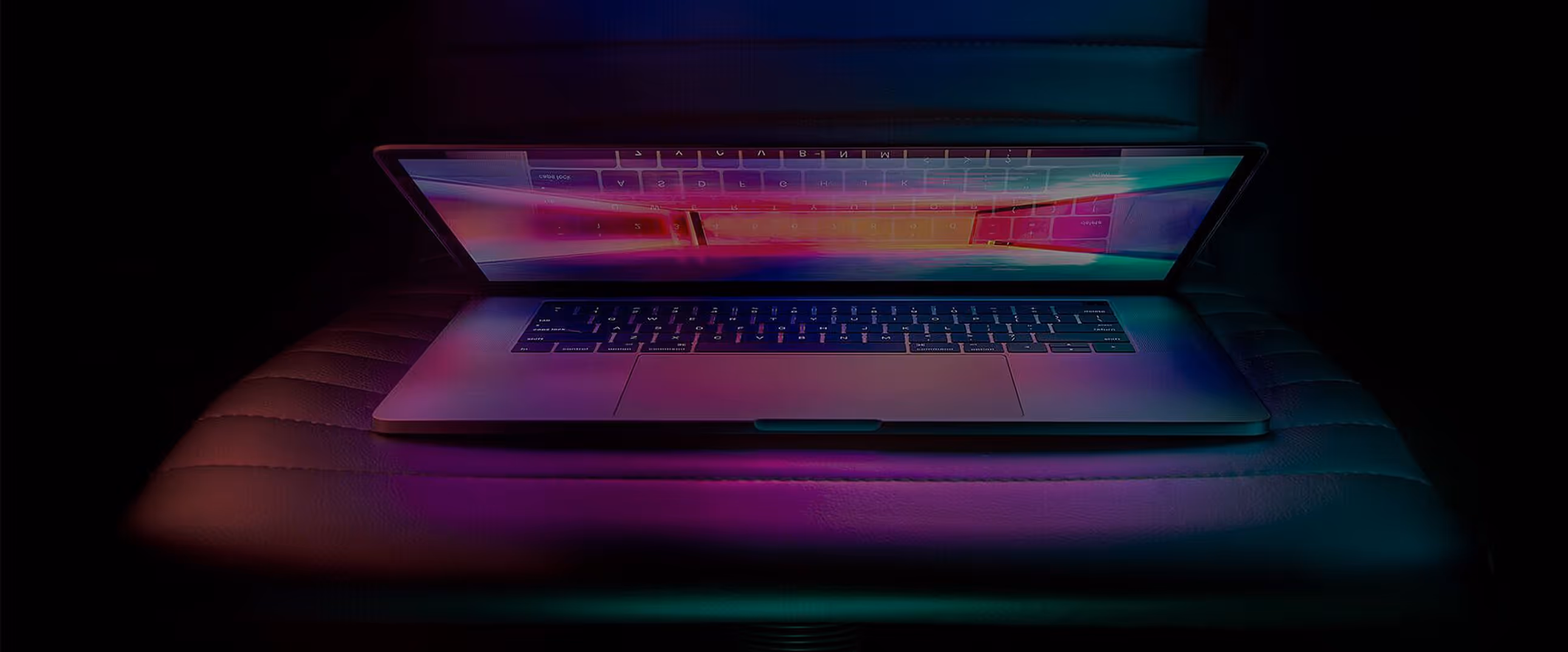 Halb geöffneter Laptop auf einem dunklen Sitz mit violett-blauem Umgebungslicht.