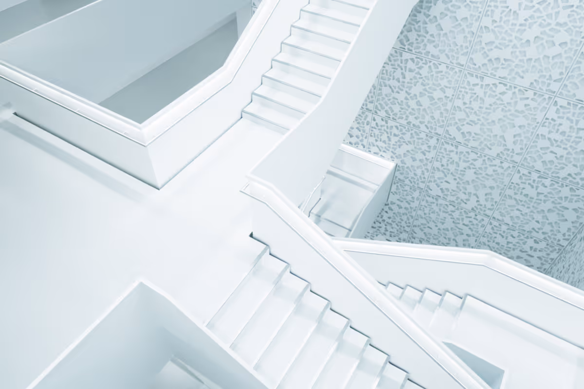 Weiße Treppen mit Geländern verbunden in einem modernen Raum mit gemusterten Wandfliesen.