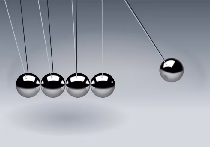 Newton-Wiege mit fünf metallischen Kugeln, eine schwingt zu den anderen vier hin.