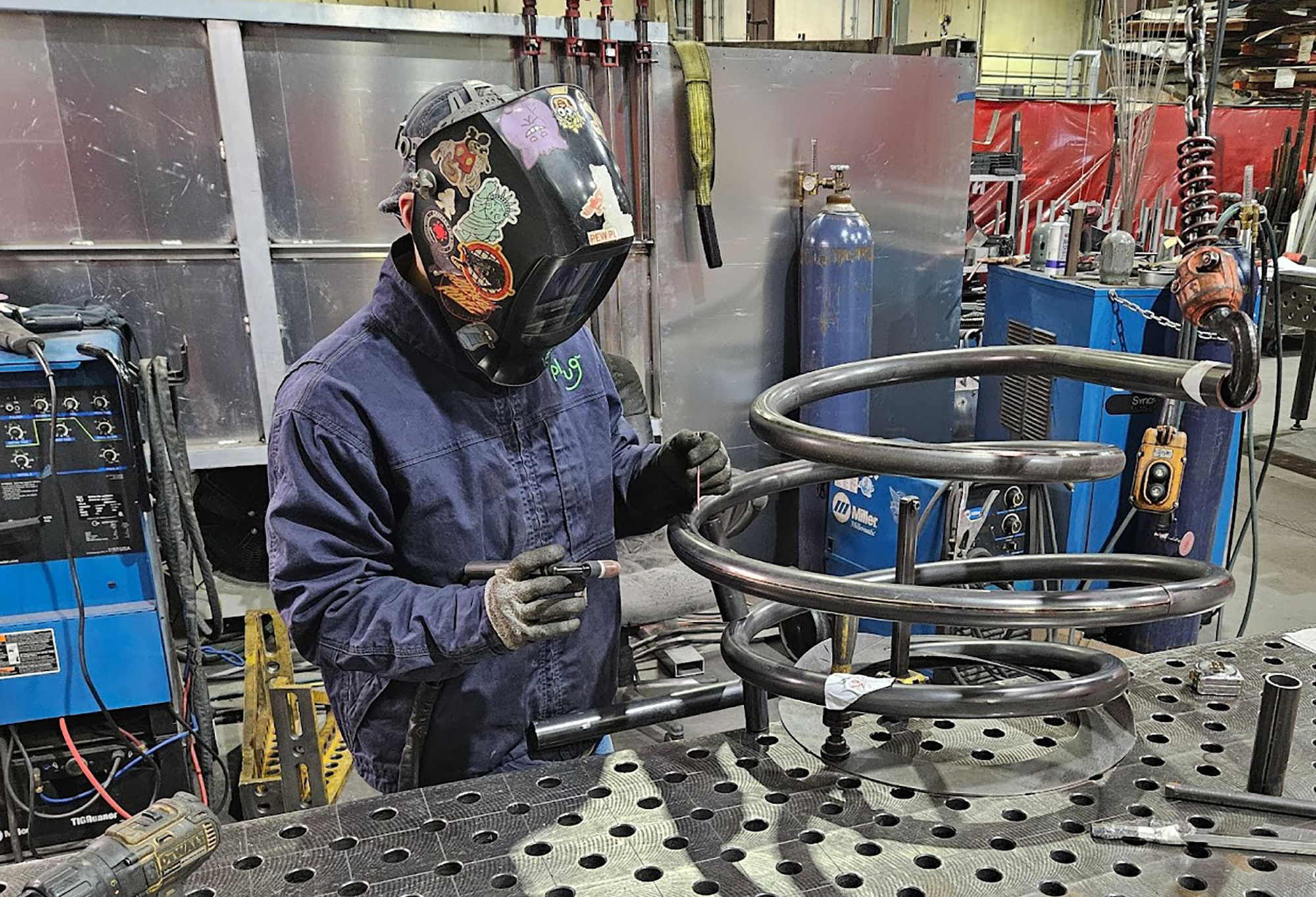 A metal worker shapes a spiral stand