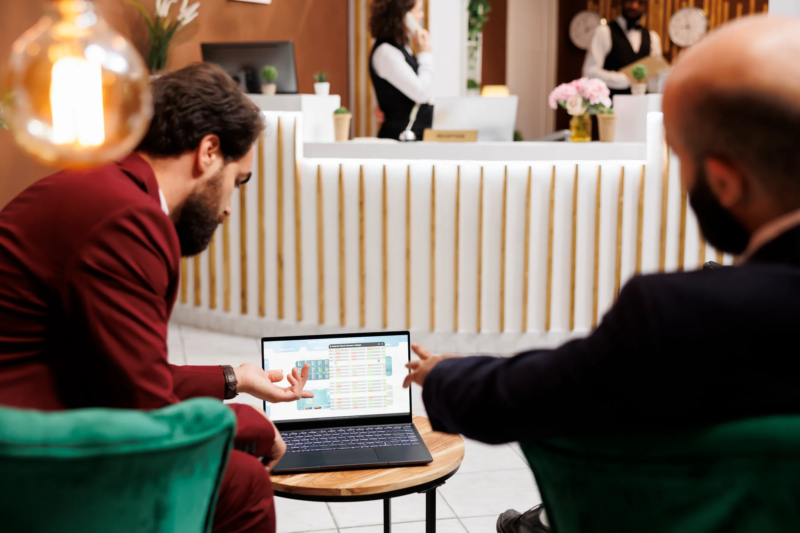 Two hotel management professionals reviewing compliance data on a laptop in a hotel lobby — repeatable hotel due diligence audit process