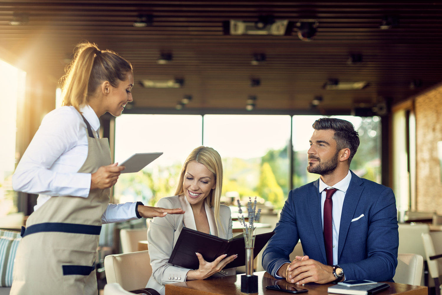 Hospitality staff serving guests in a restaurant — effective food safety training reflected in confident front-of-house competence