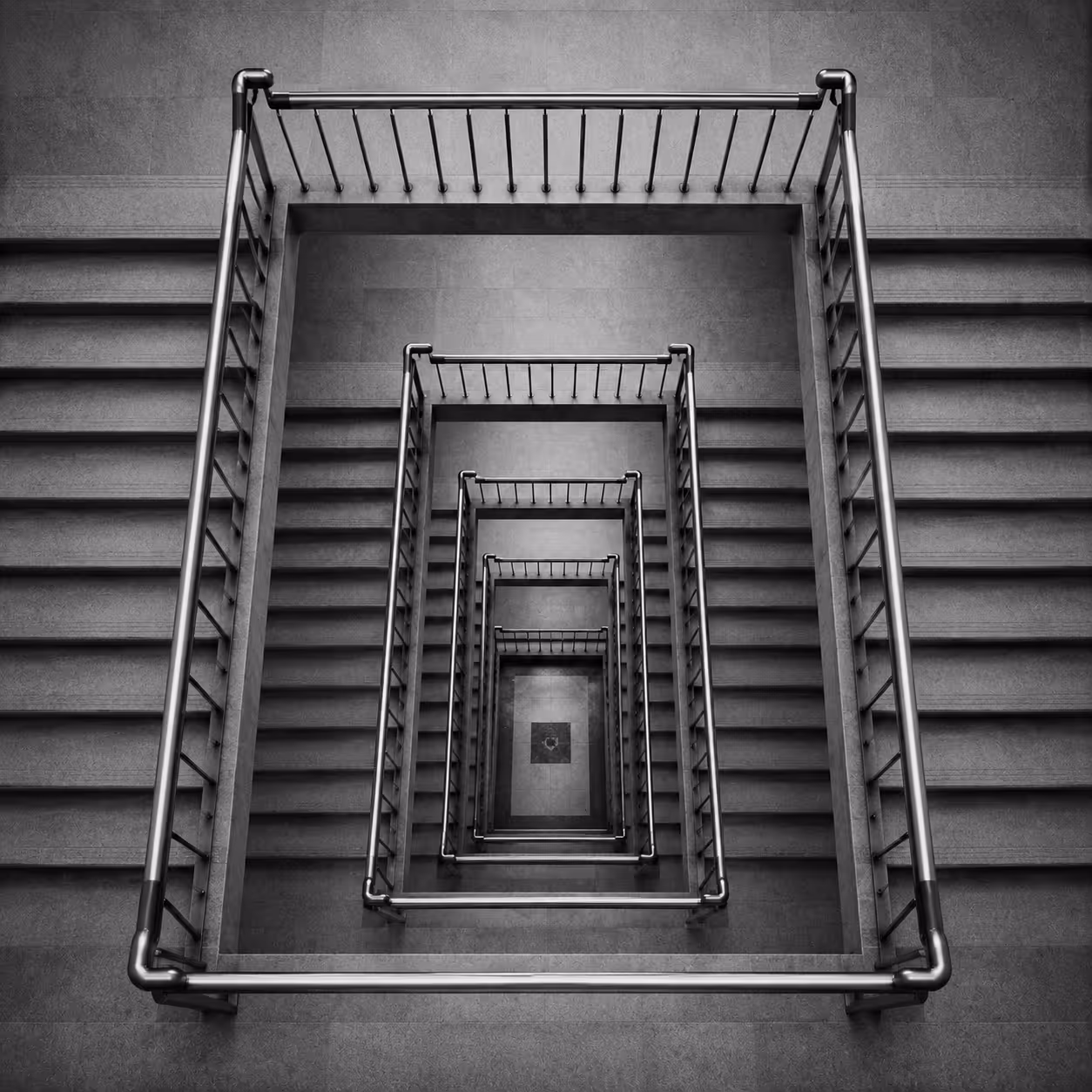 Top-down view of a square spiral staircase with metal railings in grayscale.