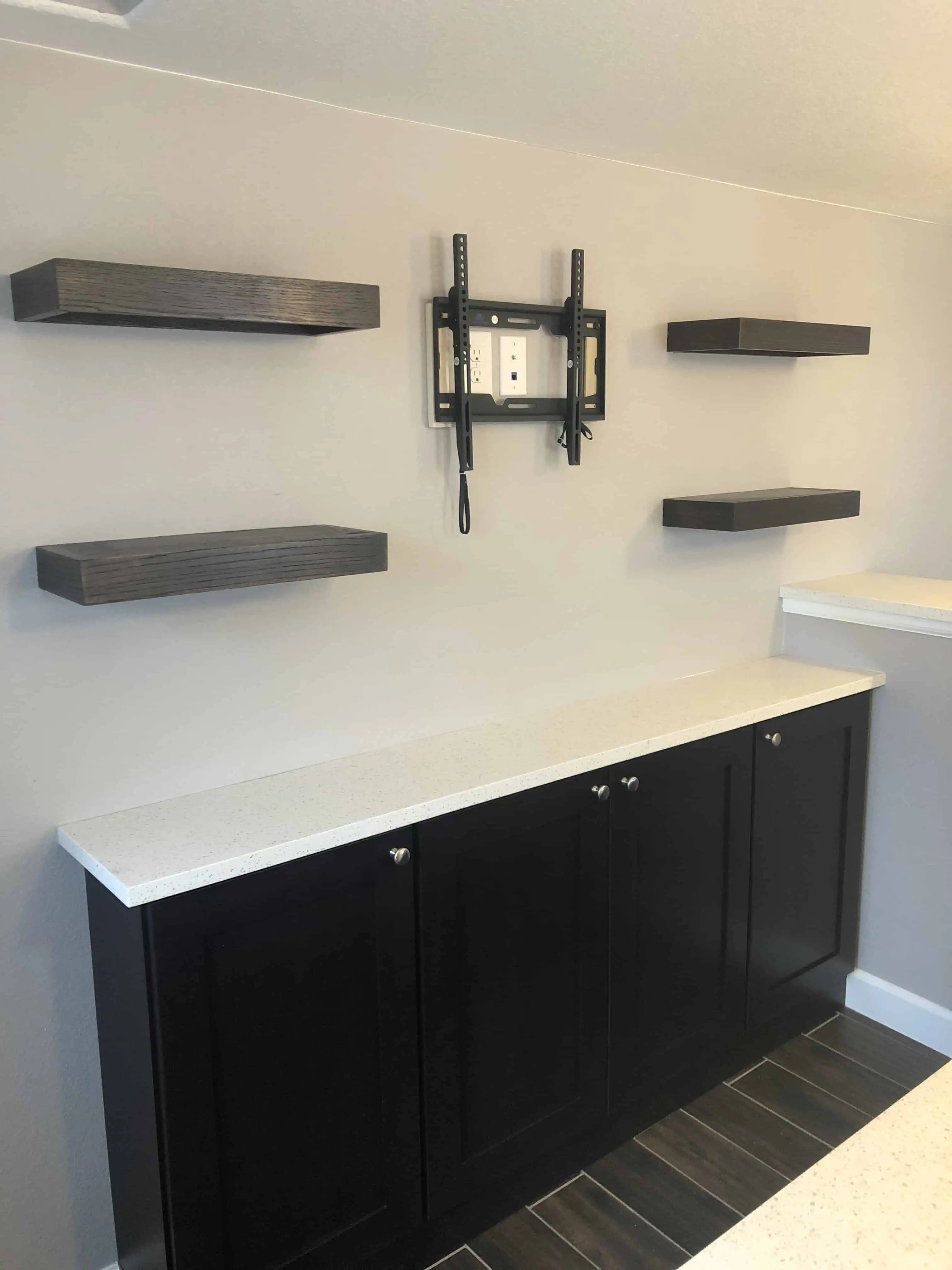 Wall-mounted TV stand with dark wooden shelves and cabinets below, showcasing modern interior design by Blue Mountain Remodeling in Denver.
