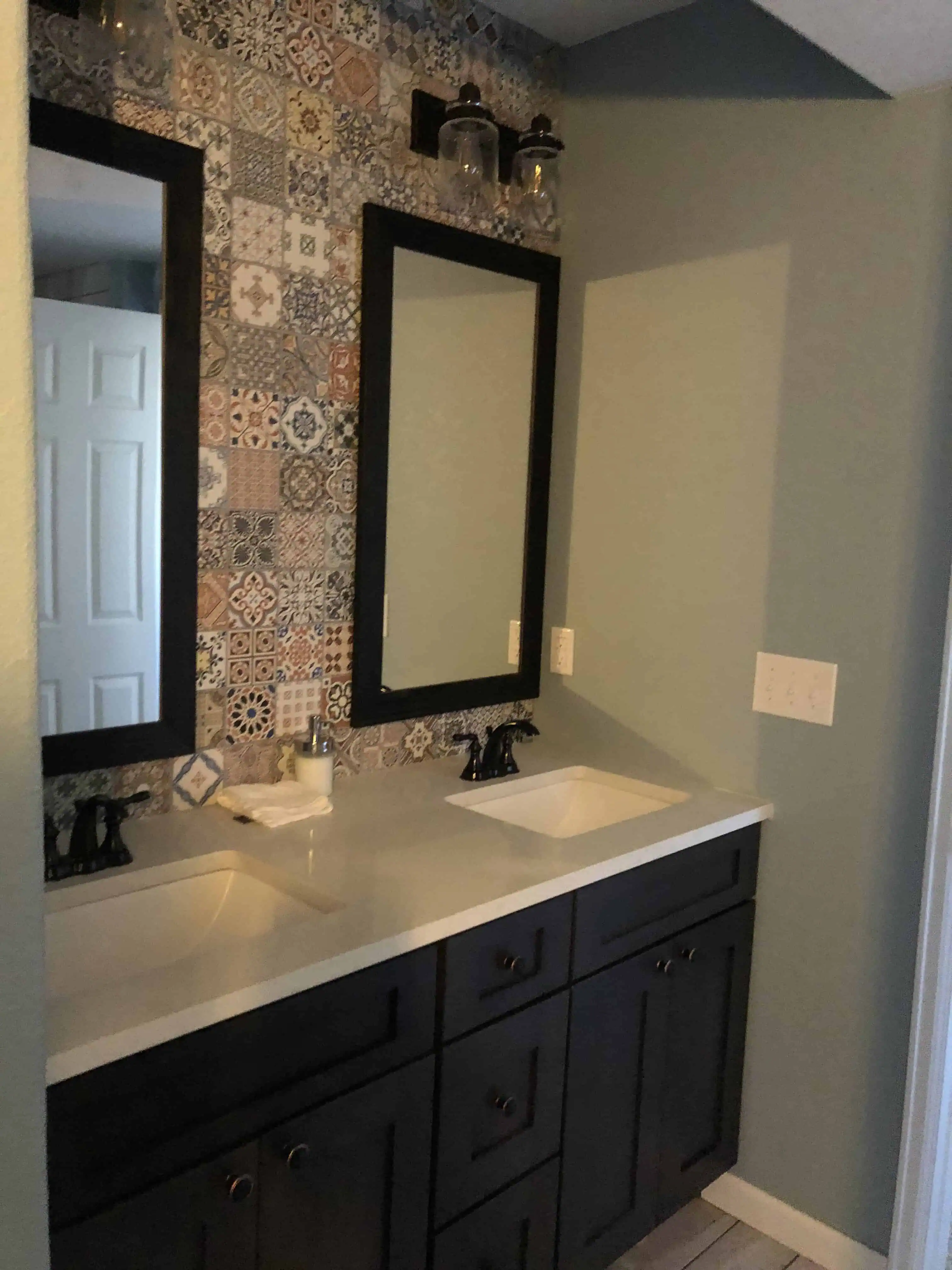 Modern bathroom renovation featuring a double vanity with dark wood cabinets, white countertop, and decorative tiled backsplash, completed by Blue Mountain Remodeling, Denver home renovation experts.