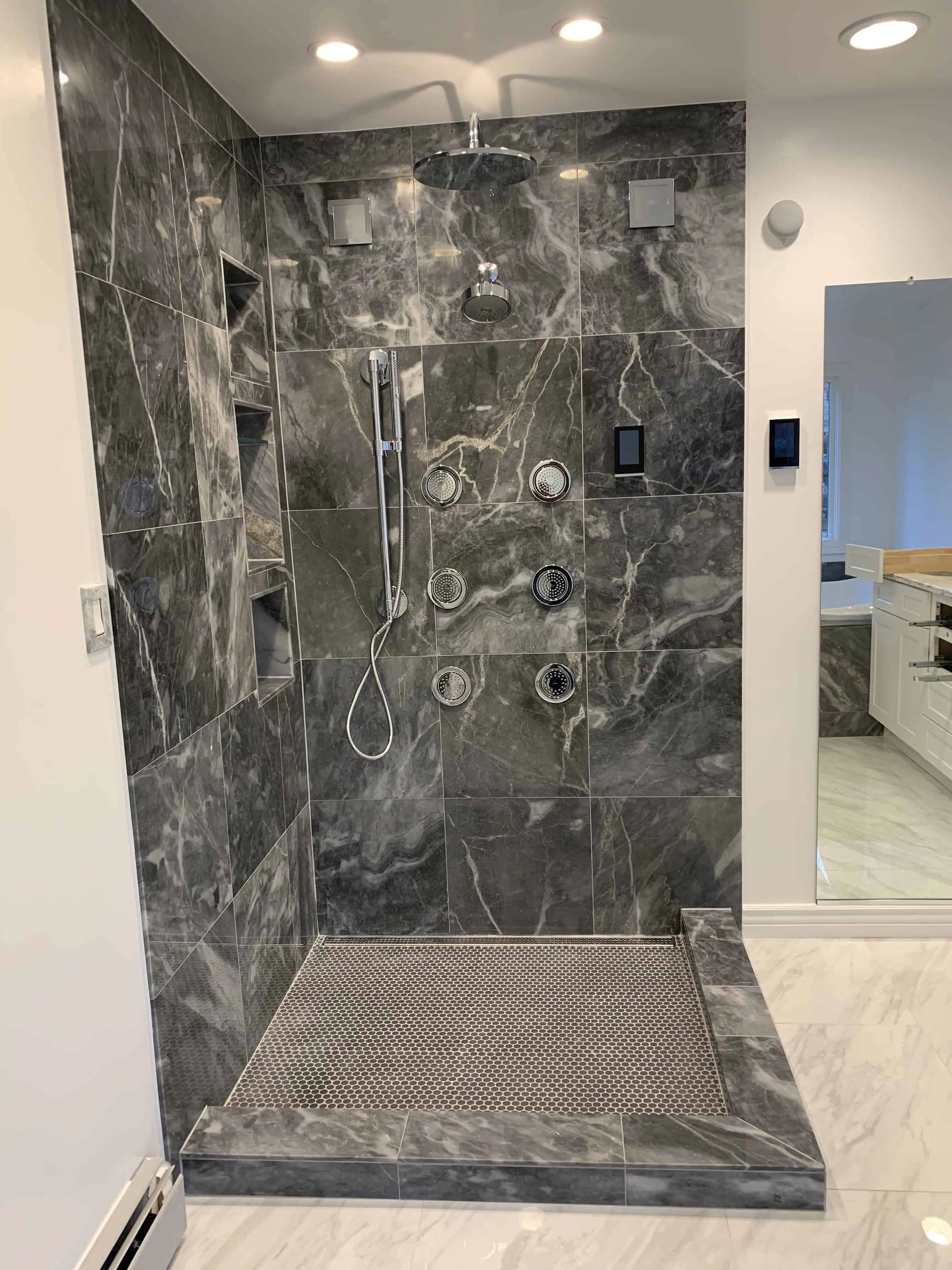 Luxurious modern shower with sleek gray marble tiles and multiple showerheads, exemplifying premium bathroom renovation by Blue Mountain Remodeling in Denver.