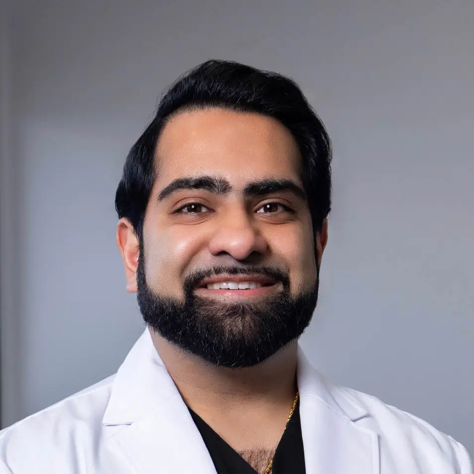 Dr. Anik Patel in a white medical coat smiling a the camera.