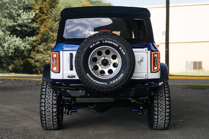 Rear of a two-tone wrapped Ford Bronco with horse emblem and spare