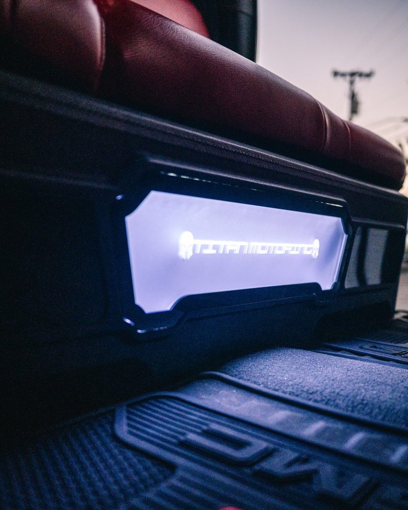 Backlit Titan Motoring acrylic panel on a custom underseat subwoofer enclosure in a GMC Sierra