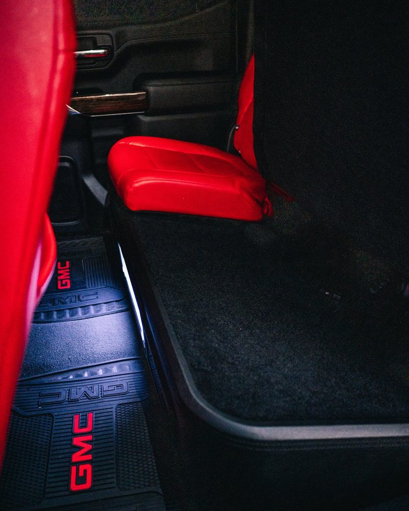 Rear row Salsa red leather and lit door sill in a GMC Sierra