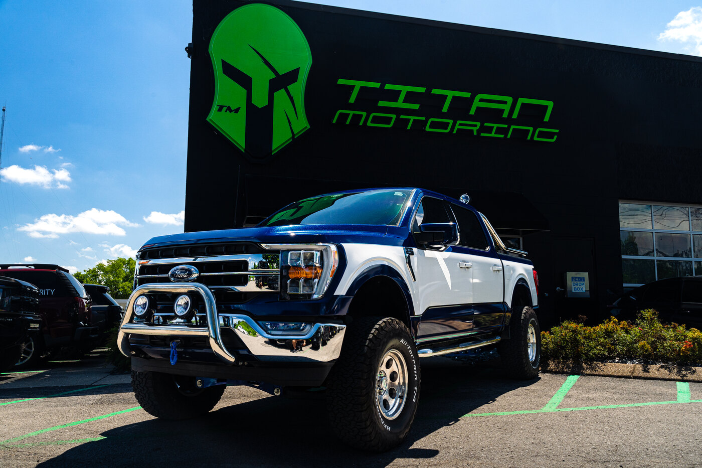 Lifted Ford F-150 Lariat with chrome bull bar and bed roll bar outside Titan Motoring, Nashville