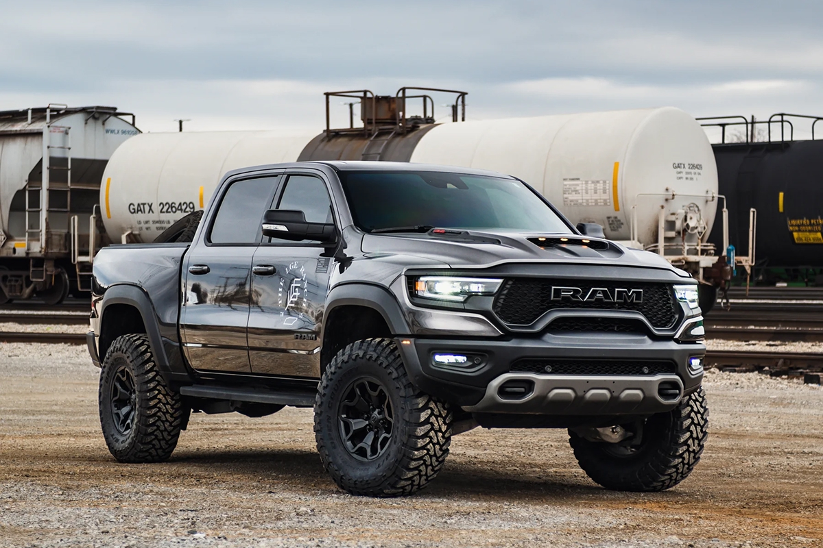 Lifted gray Ram TRX on black wheels with rail tank cars behind it