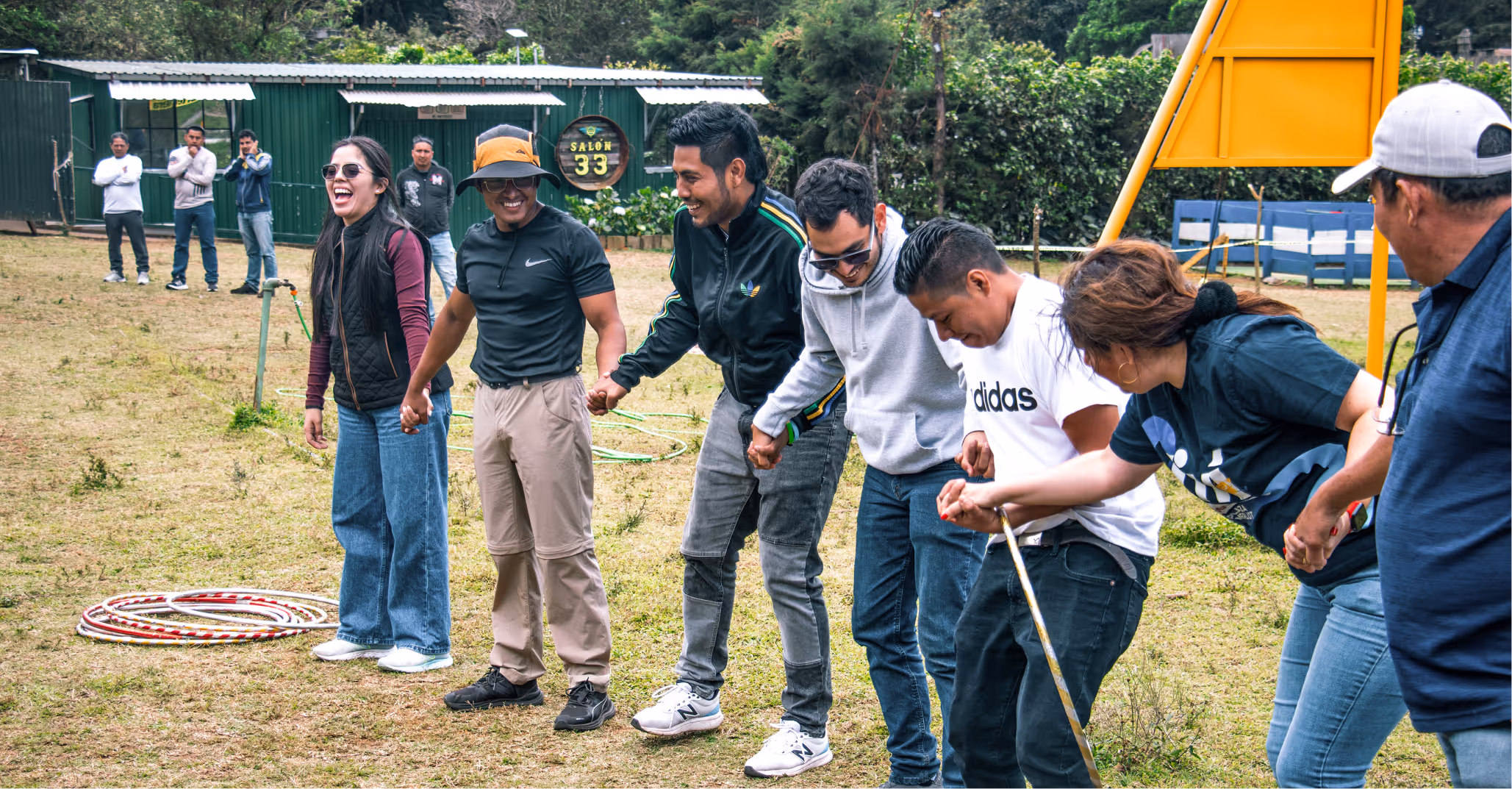 Grupo de adultos sosteniéndose de las manos formando una cadena al aire libre en un campo.