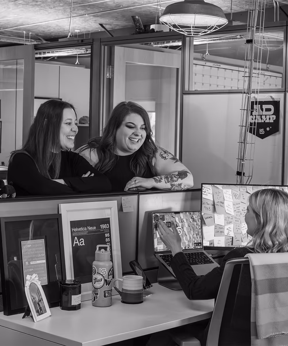 two women smiling and talking to fellow employee