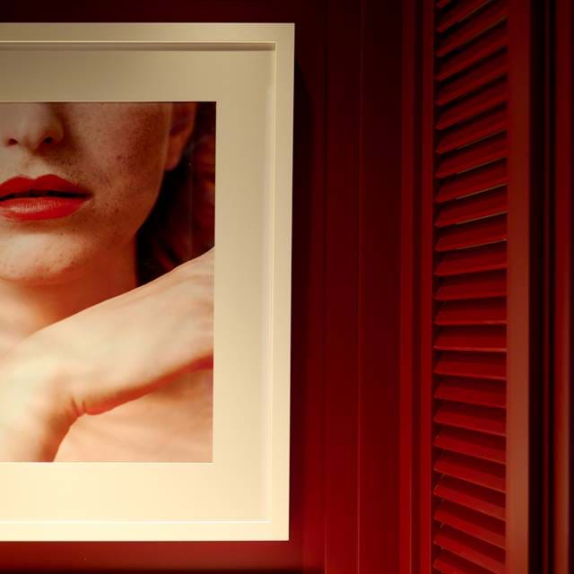 Künstlerisches Innenarchitekturdetail im AREV Hotel in St. Tropez, das ein gerahmtes Portrait vor einer tiefliegenden Wand zeigt.